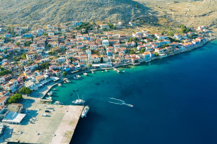 Island from above with houses along the shore and a boat leaving