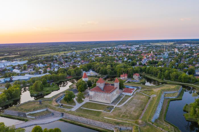 Castle on the island of Saaremaa in Estonia surrounded by walls, aerial shot with orange sky 